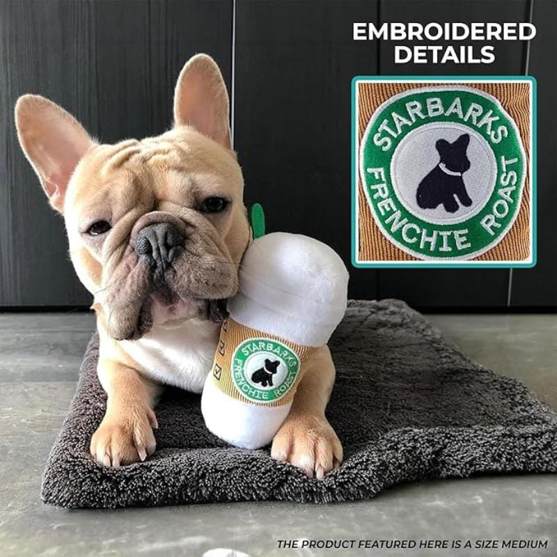 French bulldog playing with white plush coffee cup dog toy with STARBARKS patch.