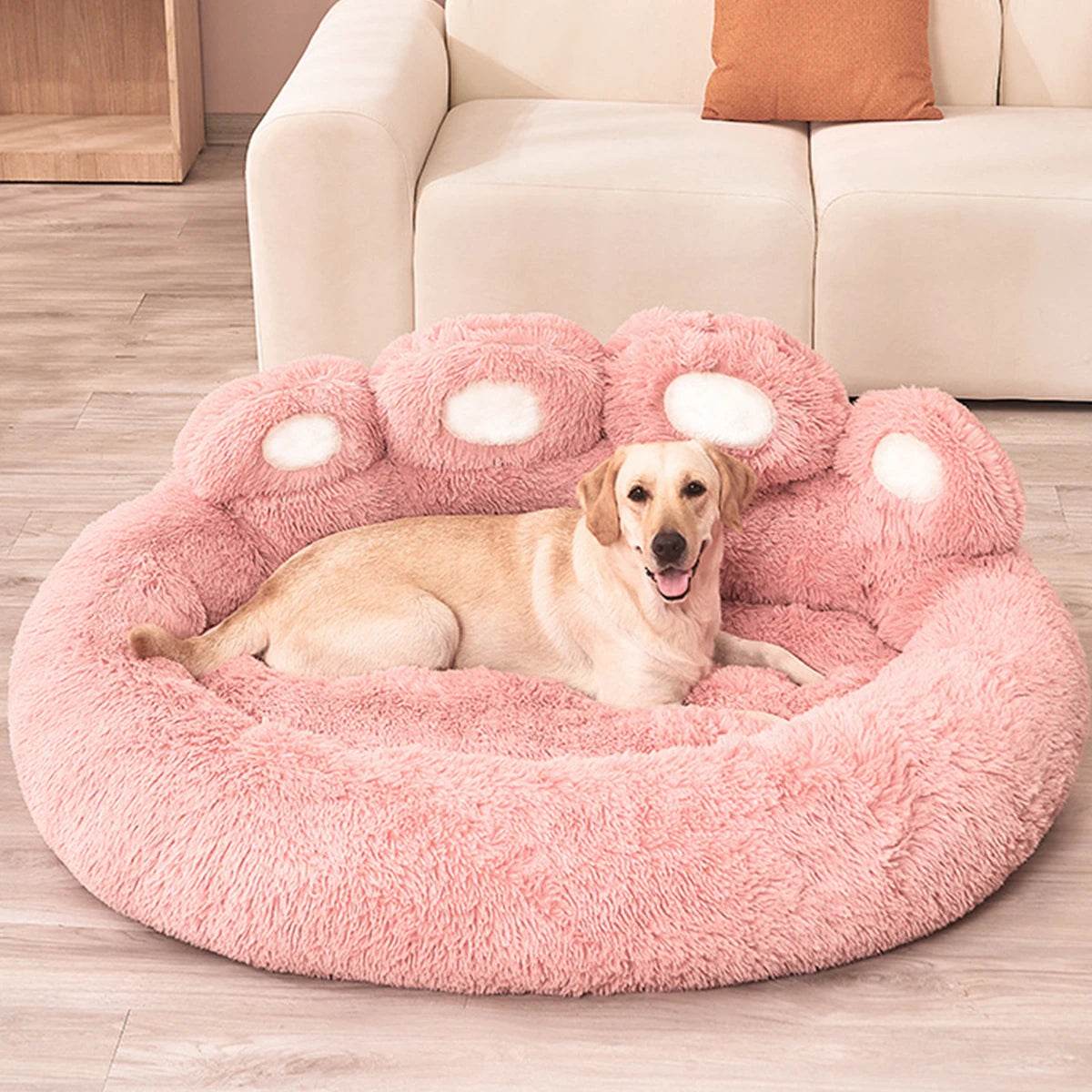 Pink round plush pet sofa bed with raised bolsters and paw-shaped accent cushions