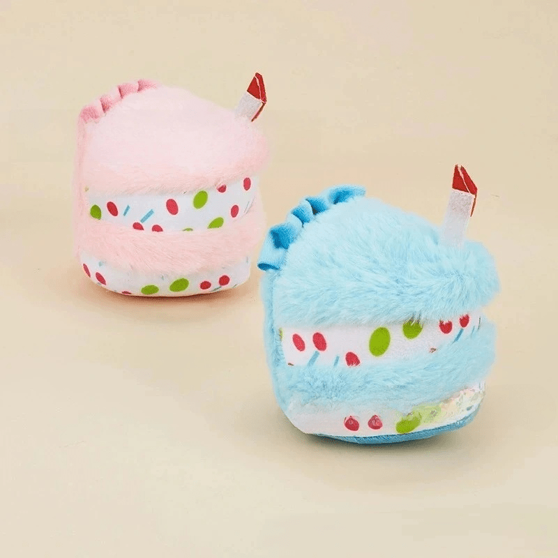 Plush birthday-cake dog toys, pink and blue, with candle toppers and sprinkle print