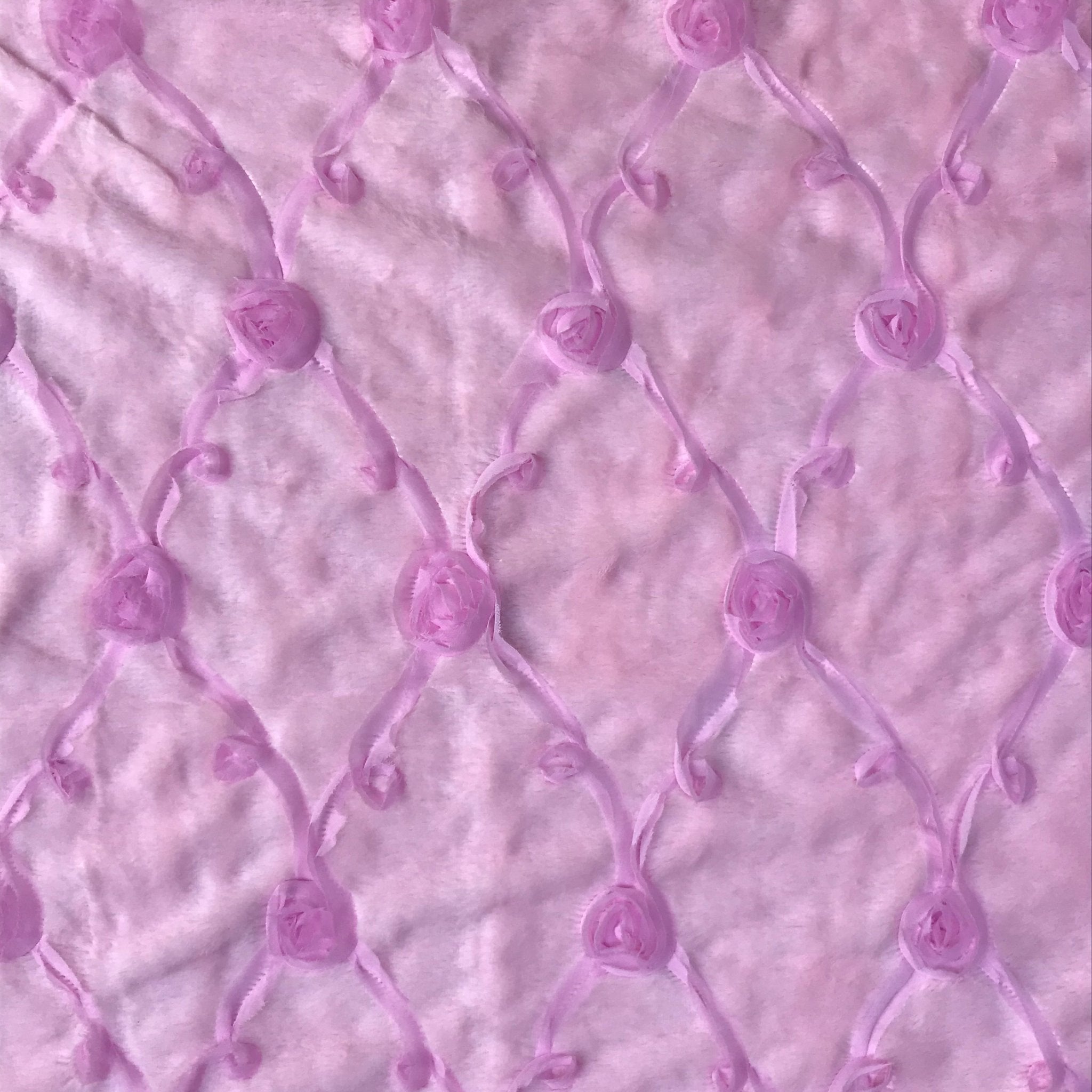 Close-up of pale pink embroidered roses on a quilted plush fabric
