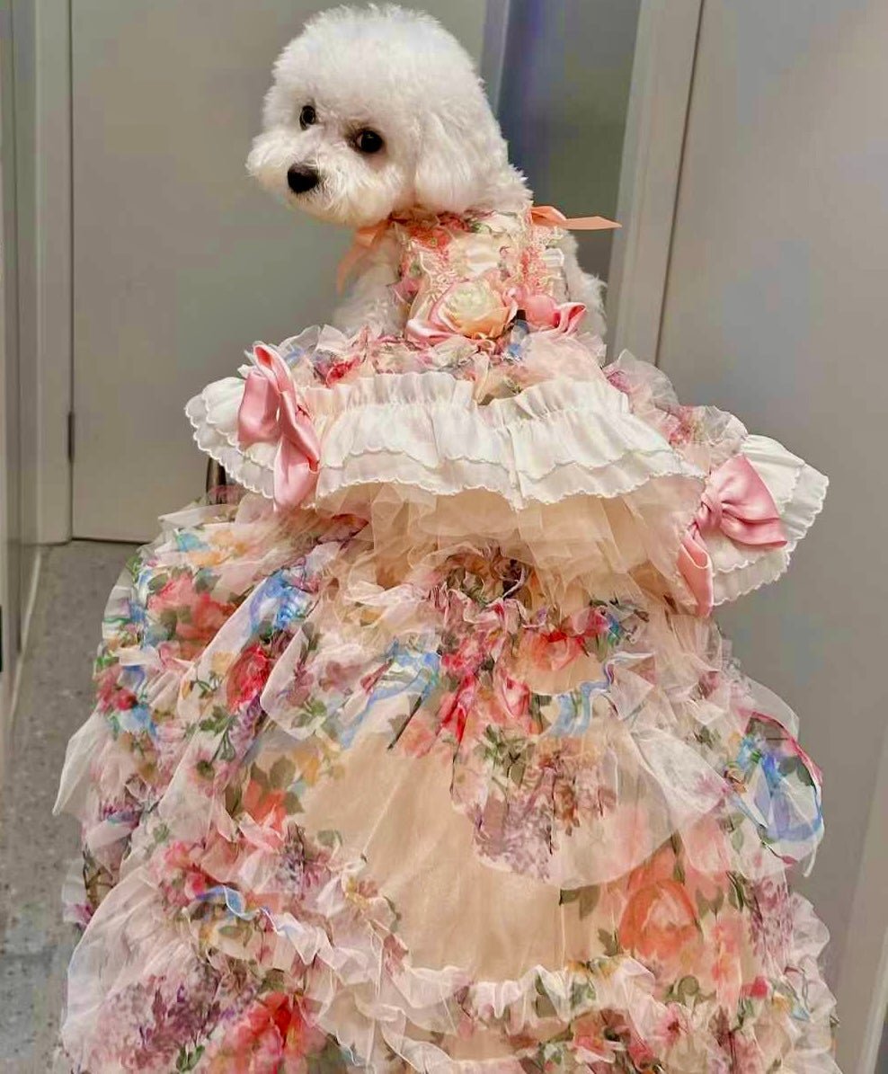 White dog wearing floral pastel ruffle wedding dress with pink bow accent