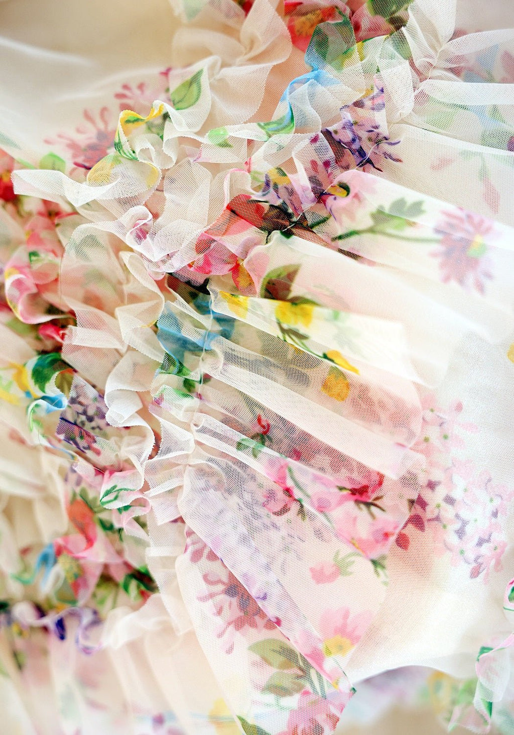 Detail view of floral pastel ruffle fabric with layered tulle and ribbon trims
