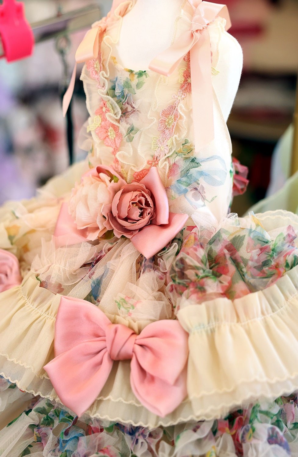 Front close-up of floral pastel dog dress with pink bow and rose embellishment