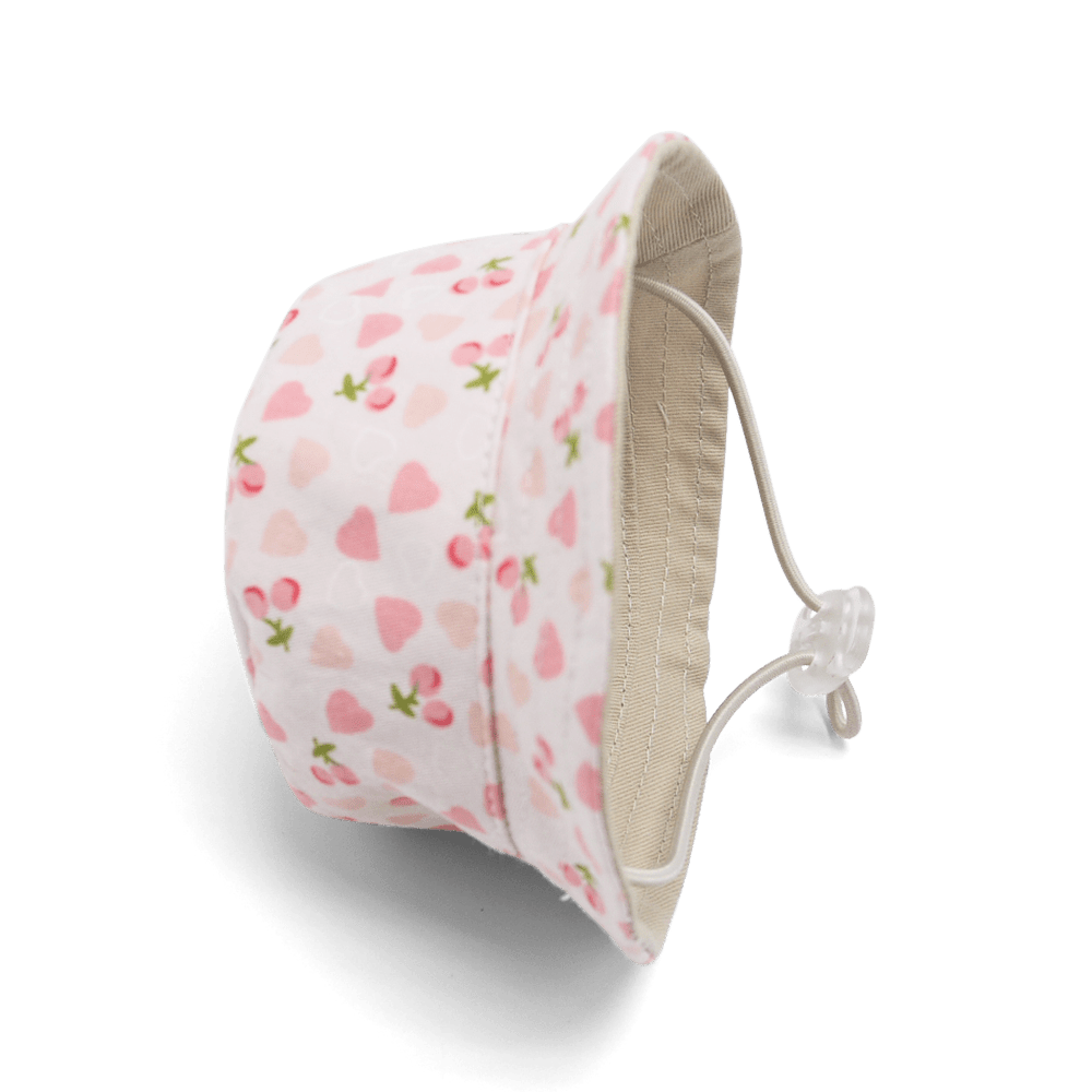 Pink heart-and-cherry bucket hat, side view with beige lining and tied drawstring