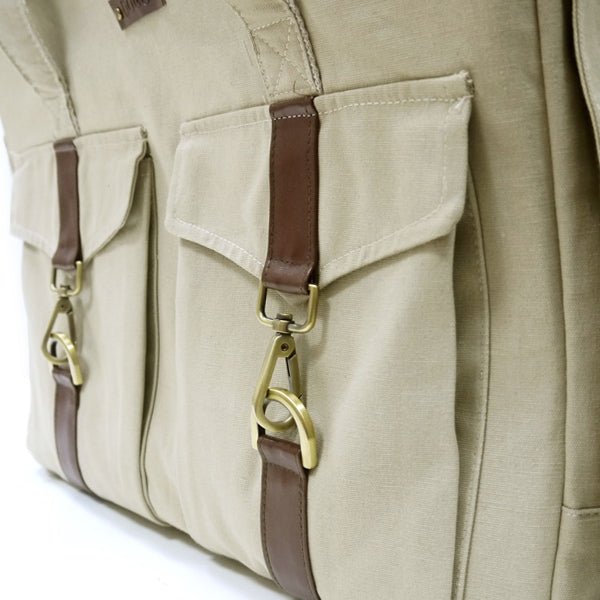 Beige buckle tote close-up: front flap pocket, brown leather tab, metal D-rings