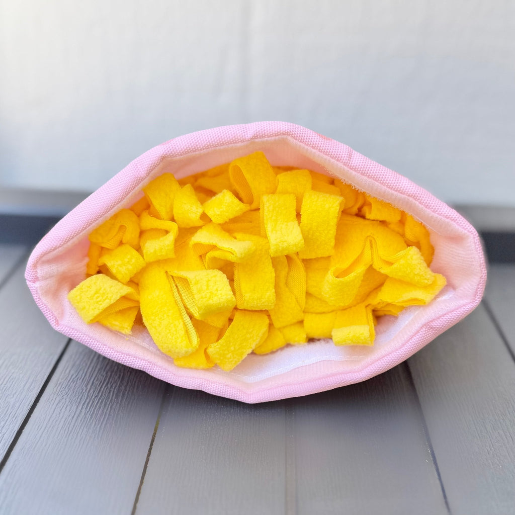 Plush ramen noodle pieces in a pink fabric bowl for dogs