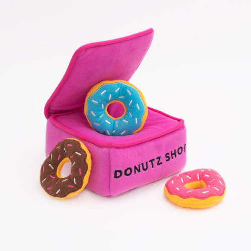 Plush interactive dog toy box with donut-shaped pieces, pink fabric and colorful toppings