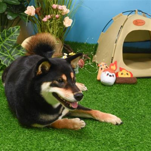 Plush camping toy set on grass: flame, white hot-dog plush, orange tent with dog nearby