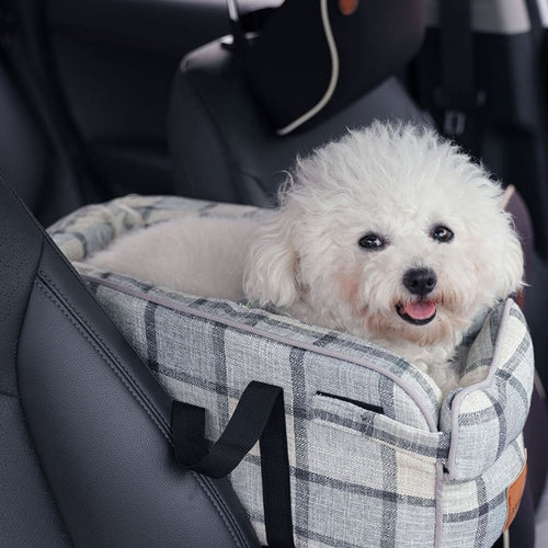 Plaid pet travel carrier bag with black straps, secured on a car seat with a small dog