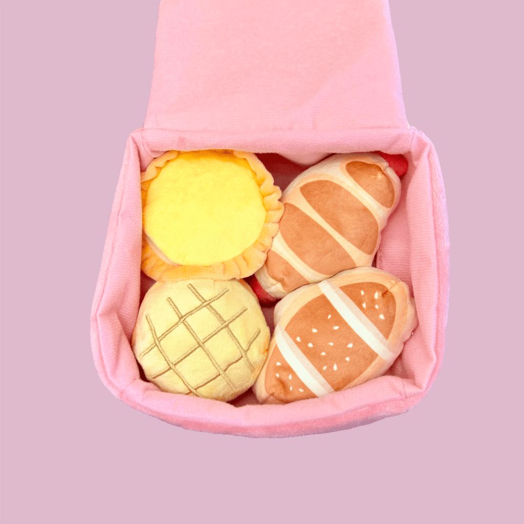 Pink plush bakery box dog toy open with four visible pastry plushes