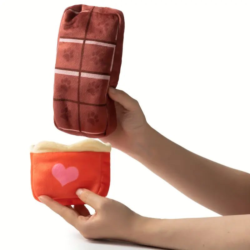 Plush candy-bar heart dog toy held in hand; brown paw-print squares with orange base