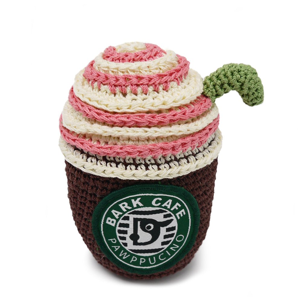 Crochet coffee cup toy with dark brown body, cream/pink striped top, green logo patch, handle