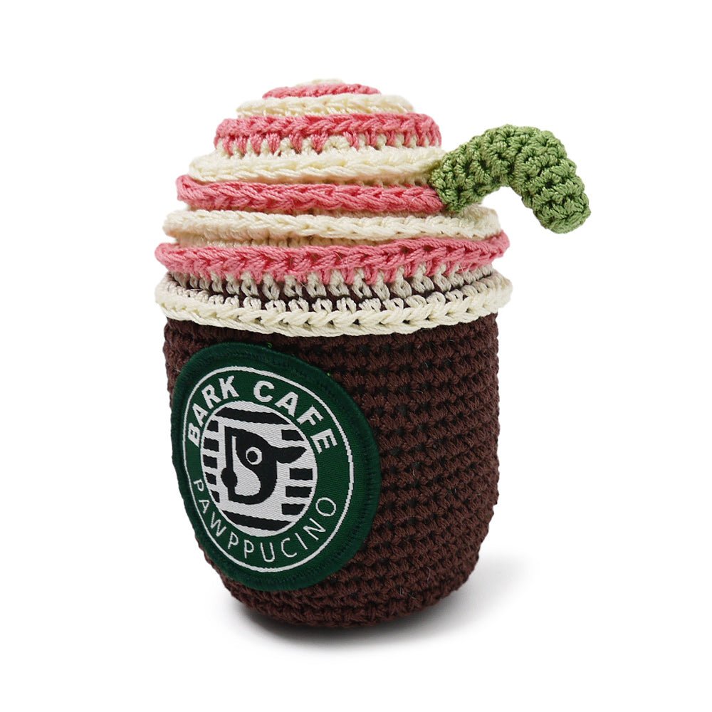 Crochet coffee cup toy with dark brown body, cream/pink stripes, green logo patch, handle