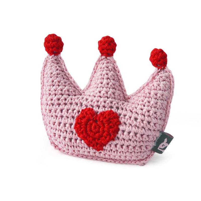 Crocheted pink crown toy with red pom-poms and red heart patch
