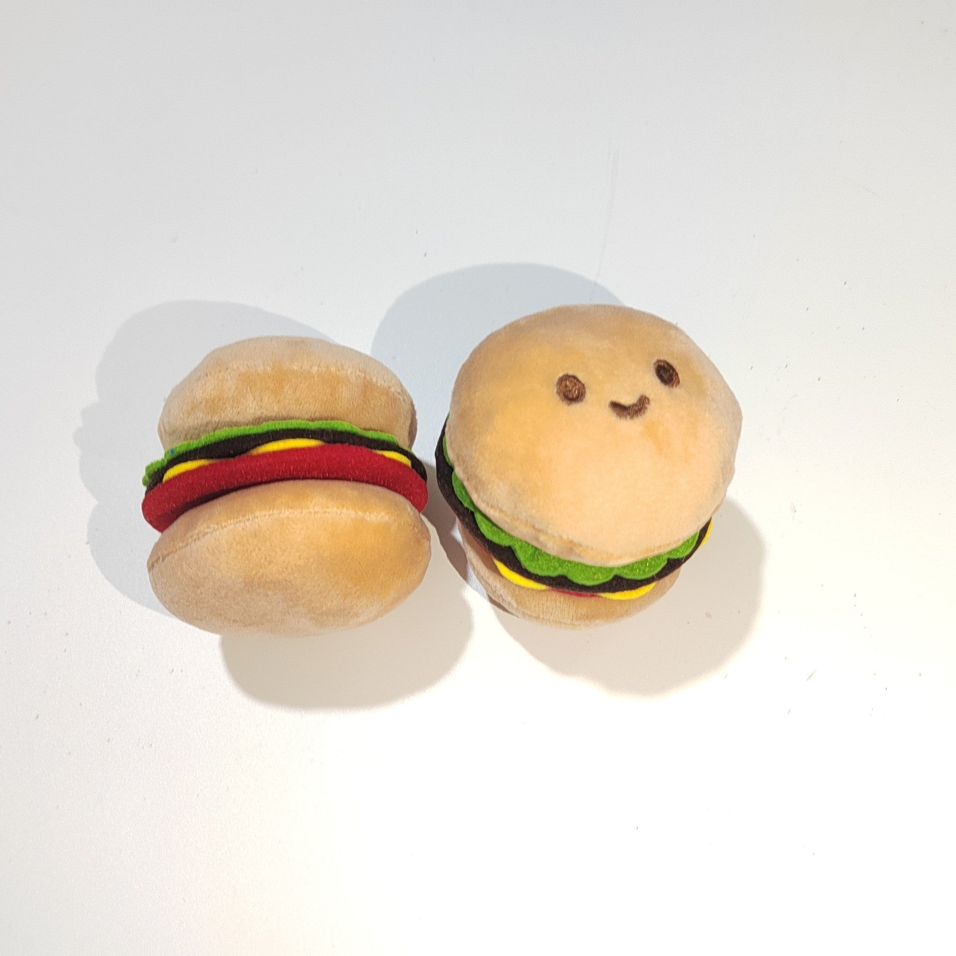 Two plush burger-shaped pet sound toys: one round bun and one layered mini burger