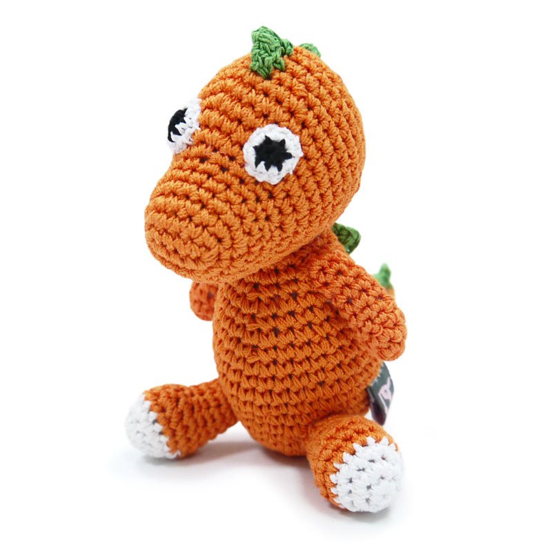 Crochet dinosaur toy, orange body with green spikes and white-and-black eyes, sitting pose