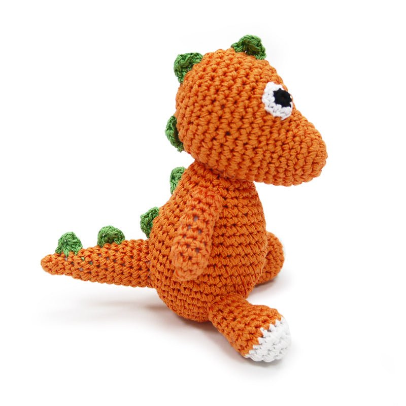 Orange crochet dinosaur toy with green spikes, white claws, and black-and-white eye patch detail