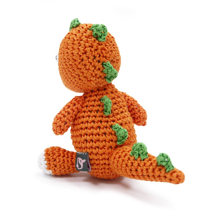 Crochet dinosaur toy with orange body, green spikes, and small stitched patch on side/belly