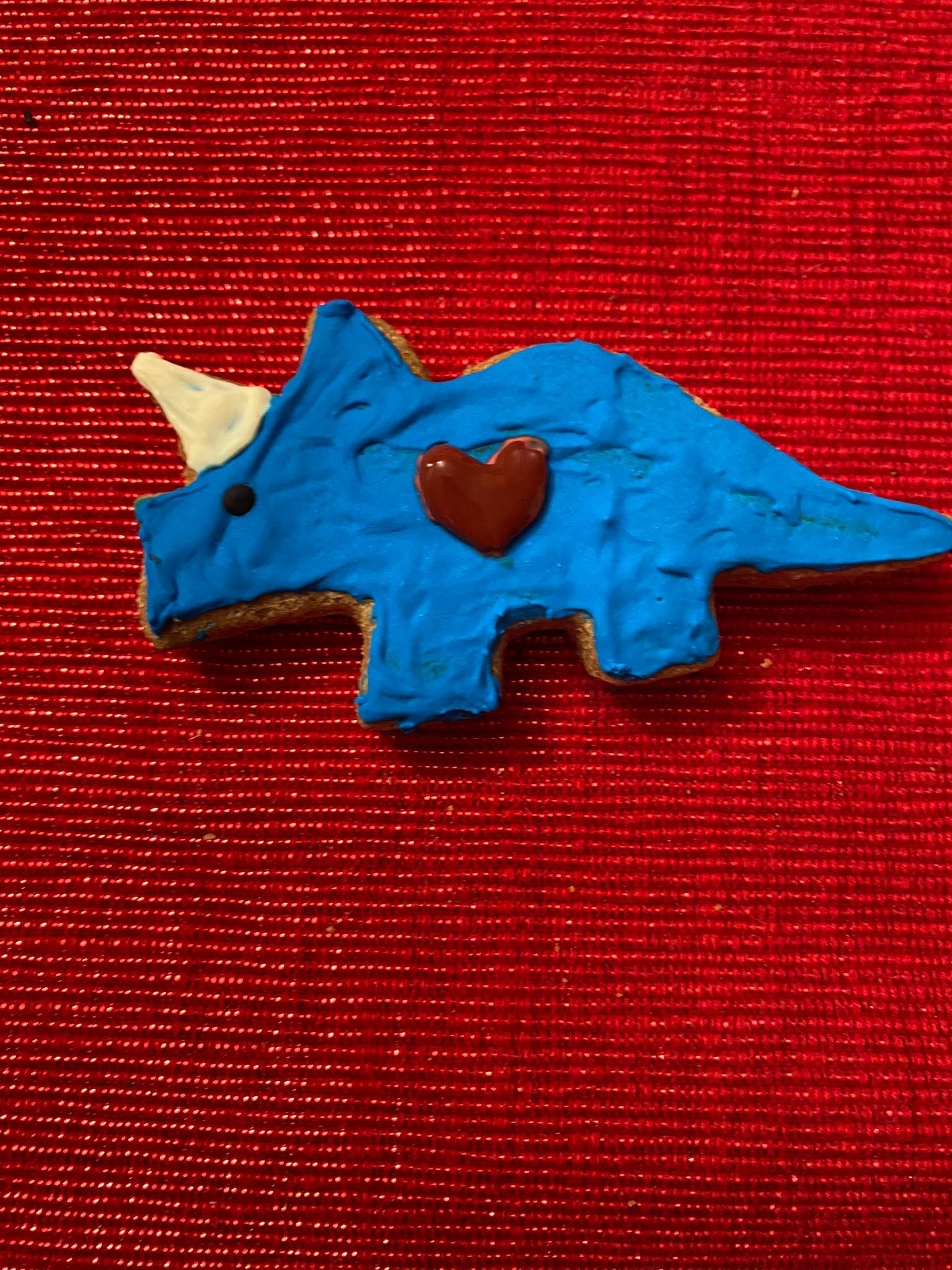 Blue dinosaur-shaped dog cookie with a red heart detail in the center