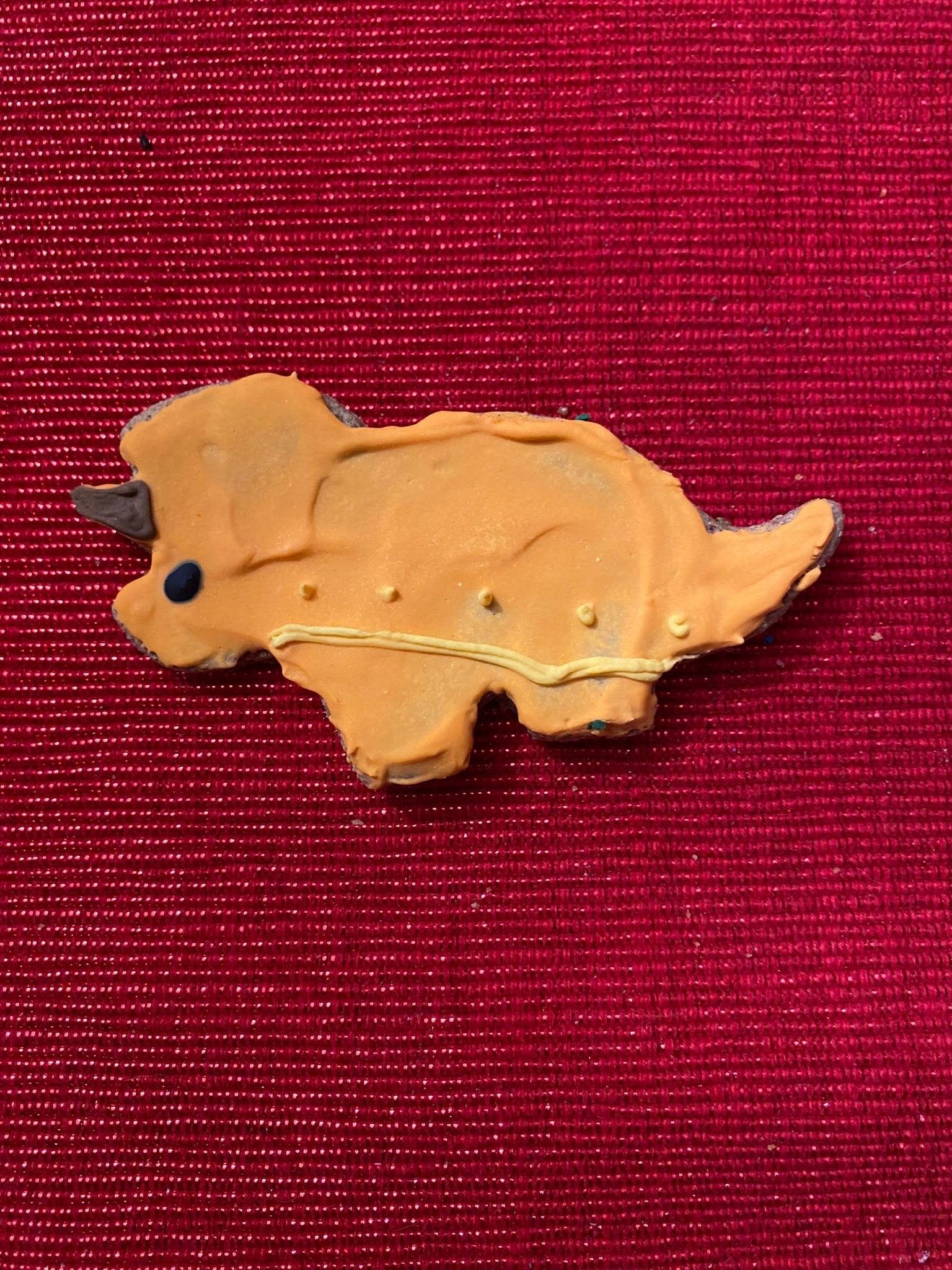 Tan dinosaur-shaped dog cookie with molded details, organic treat