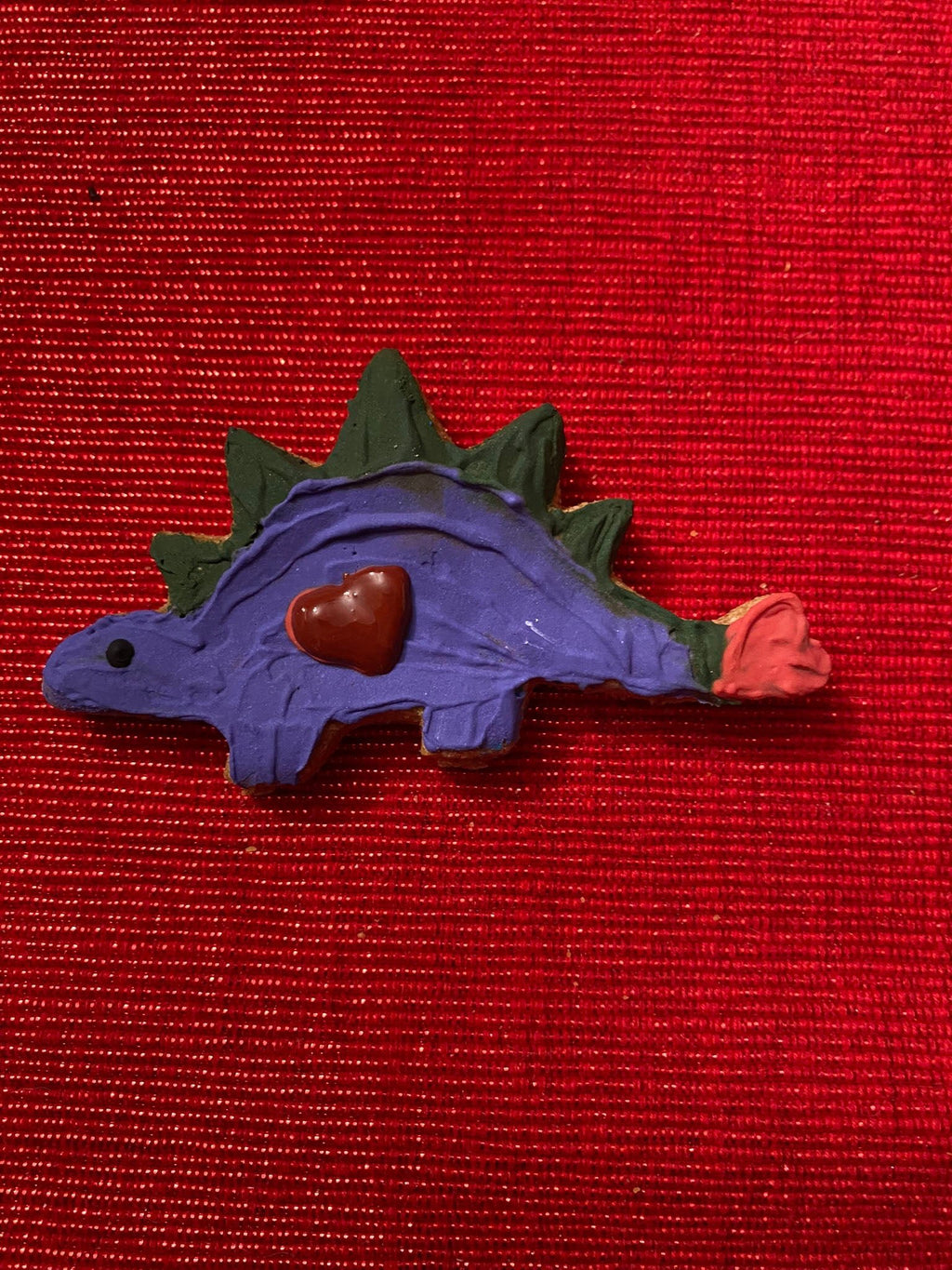 Purple dinosaur-shaped dog cookie with green spikes and a red heart detail