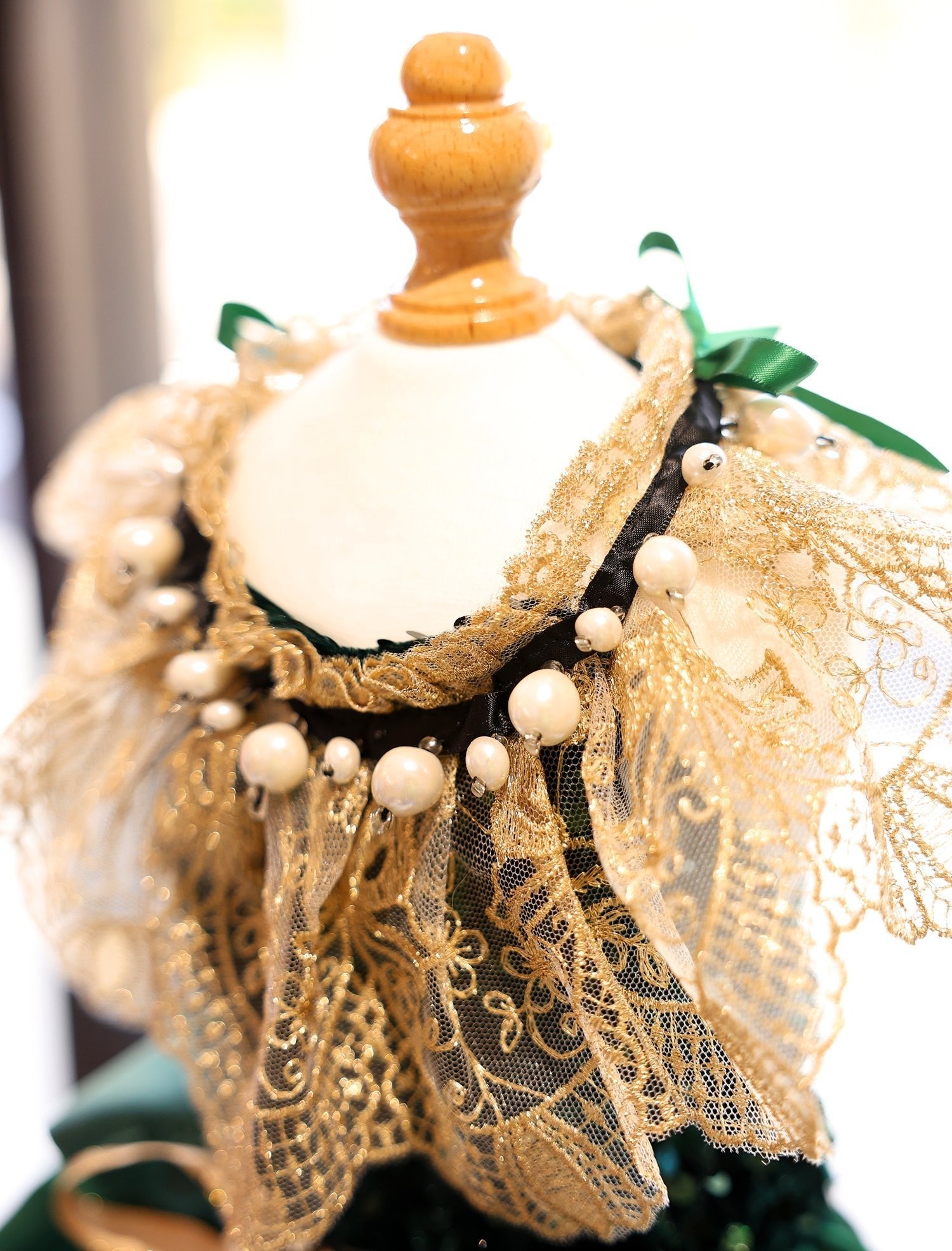 Gold lace collar with pearl bead fringe and green ribbon bows on a dark green dress