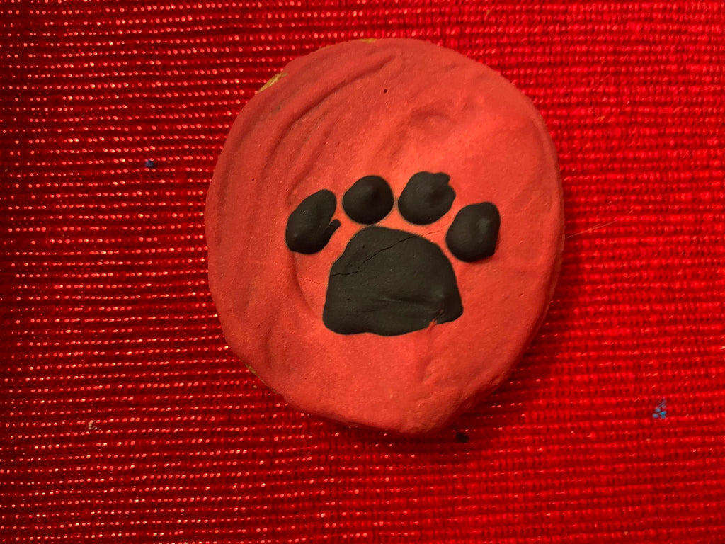 Round dog paw print cookie in orange-red with black paw logo