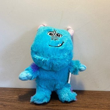 Blue plush dog toy monster with big embroidered eyes and smiling face, standing.