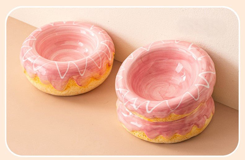 Two pink donut ceramic pet bowls with white swirl lines and yellow base glaze