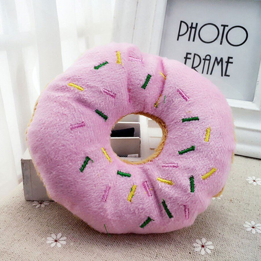 Pink plush donut pet toy with multicolor sprinkle stitching and a round center hole