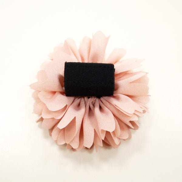 Pink fabric flower rosette with black square backing.