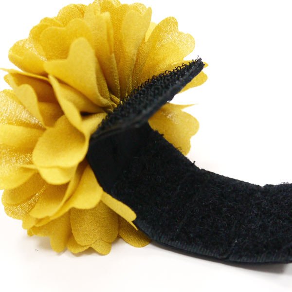Yellow fabric flower rosette with black strap attachment.