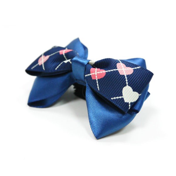 Blue bow tie with navy heart-and-ring motif, angled view with center knot