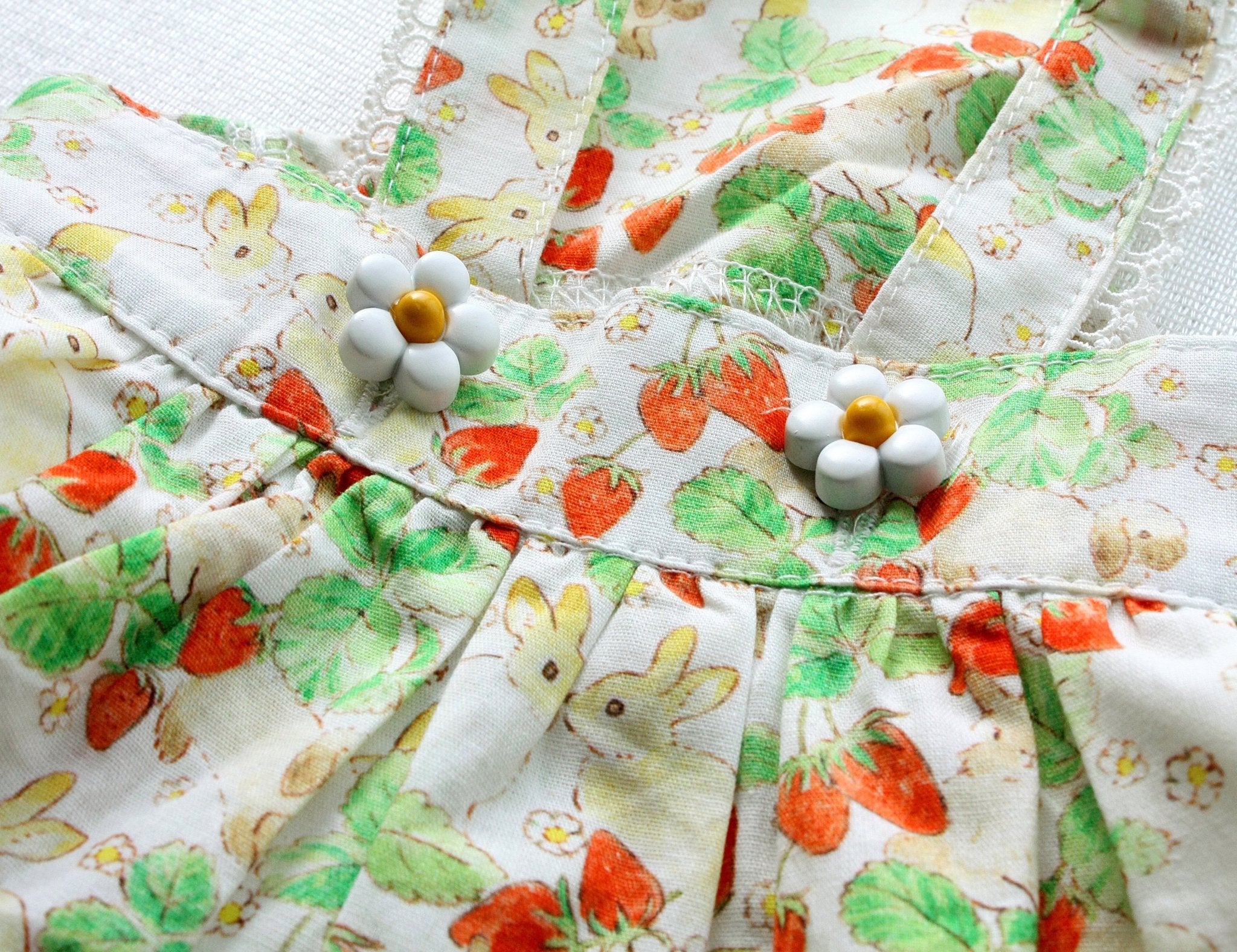 Close-up of floral rabbit-print pet dress bodice with white pom-pom buttons