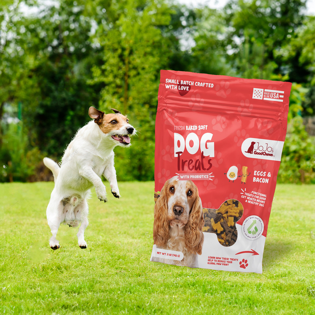 Red soft dog treat pouch labeled eggs & bacon, shown with dogs outdoors on grass