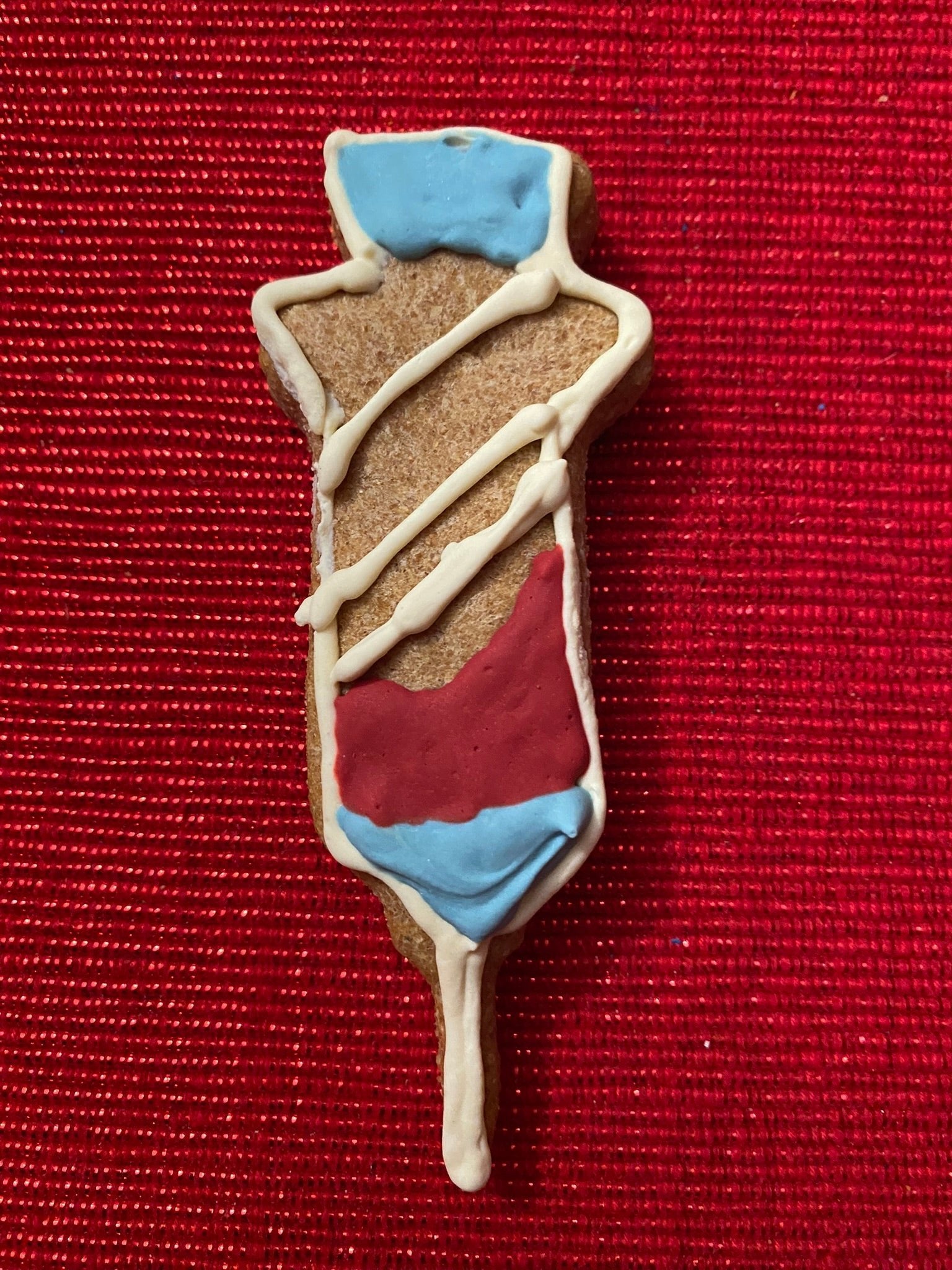 Dog-themed body cookie with blue top, red pants, and white drizzled lines