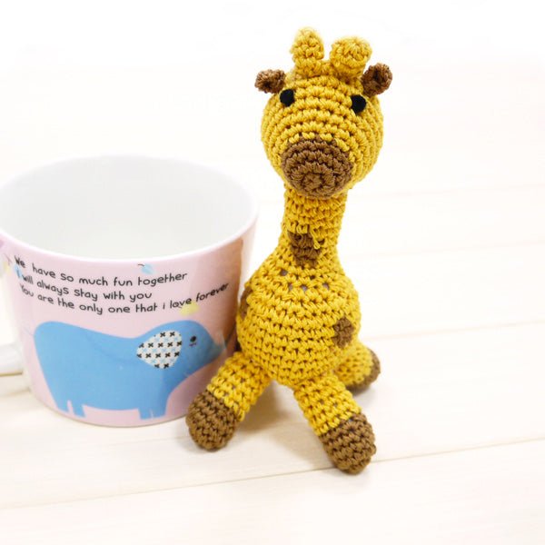 Crochet giraffe plush leaning forward, brown patches, long neck and legs