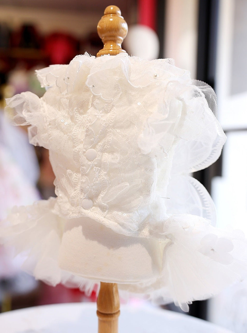 White pet dress on stand with layered tulle skirt and pearl bead embellishments