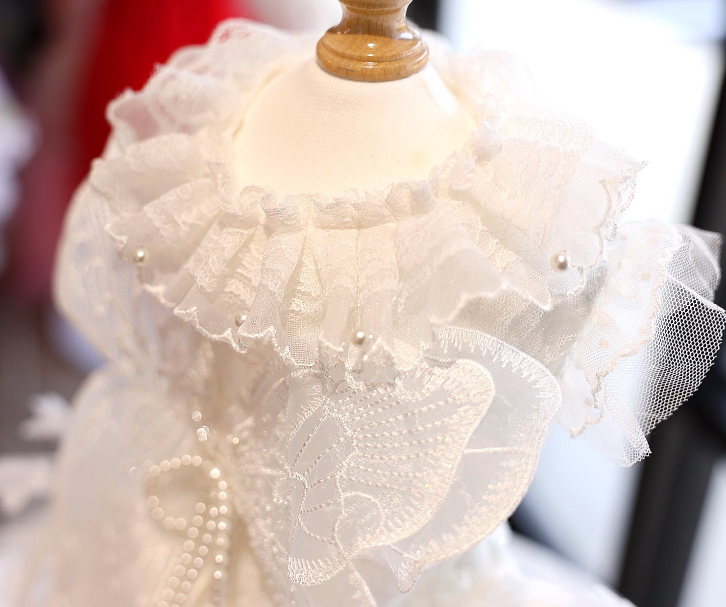 White pet dress close-up with floral lace, pearl beads, and ruffle trim