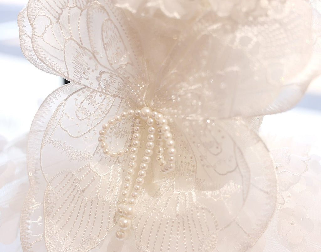 Close-up: white pet dress with embroidered butterfly wings and pearl bead drop