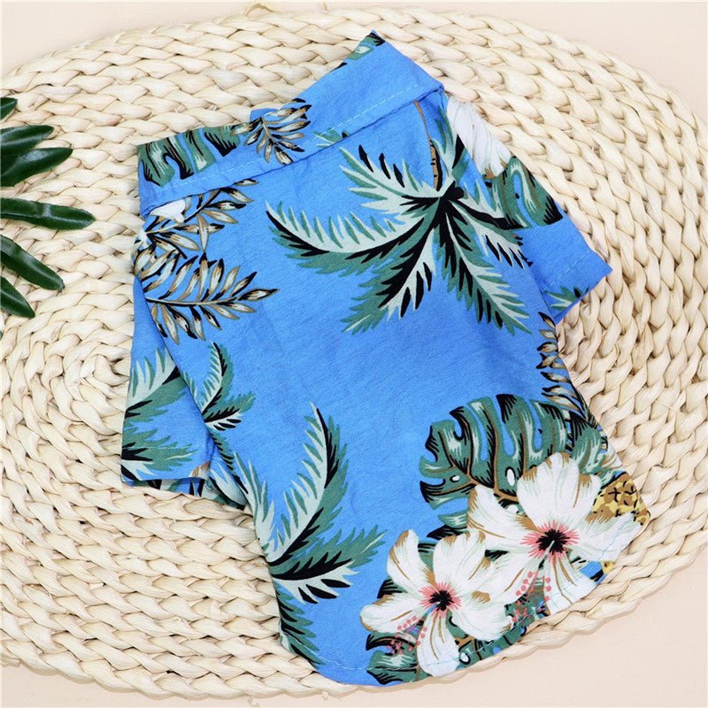 Small dog shirt in blue with green leaves and pink-white flowers tropical print.