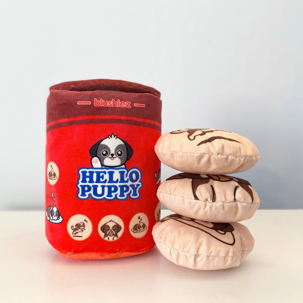 Red plush cylindrical dog toy with “Hello Puppy” graphic and three beige round toys