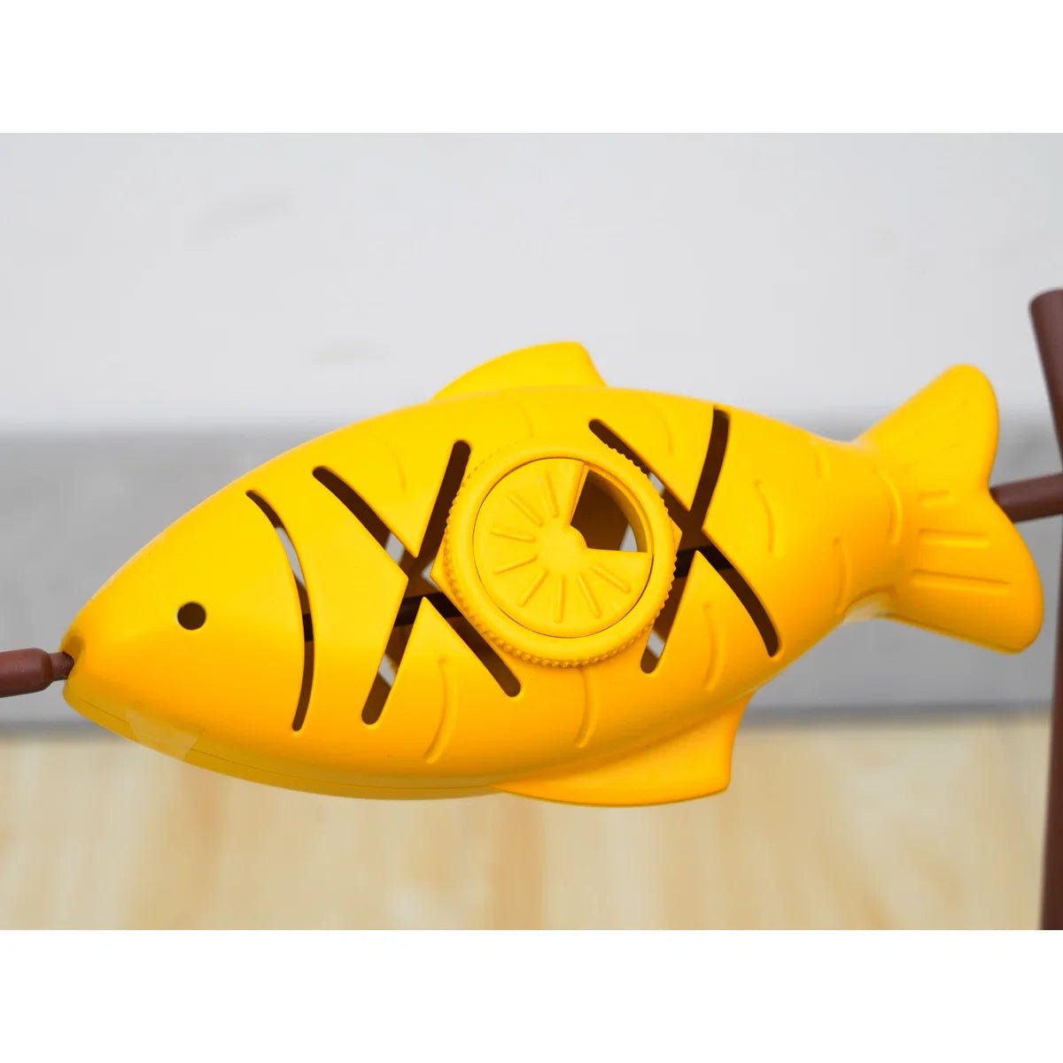 Yellow fish puzzle toy with raised circular piece and brown accents on a gray base