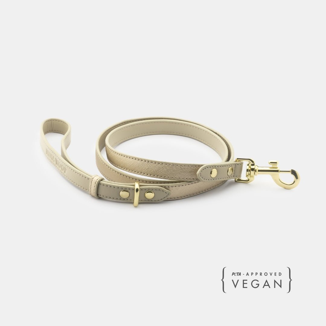 Beige vegan leather dog leash with gold clasp, rings, and adjustable hole rows.