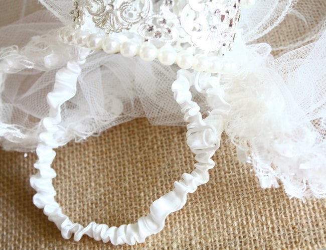 White ruffled tulle trim with pearl beading and crown embellishment, close-up