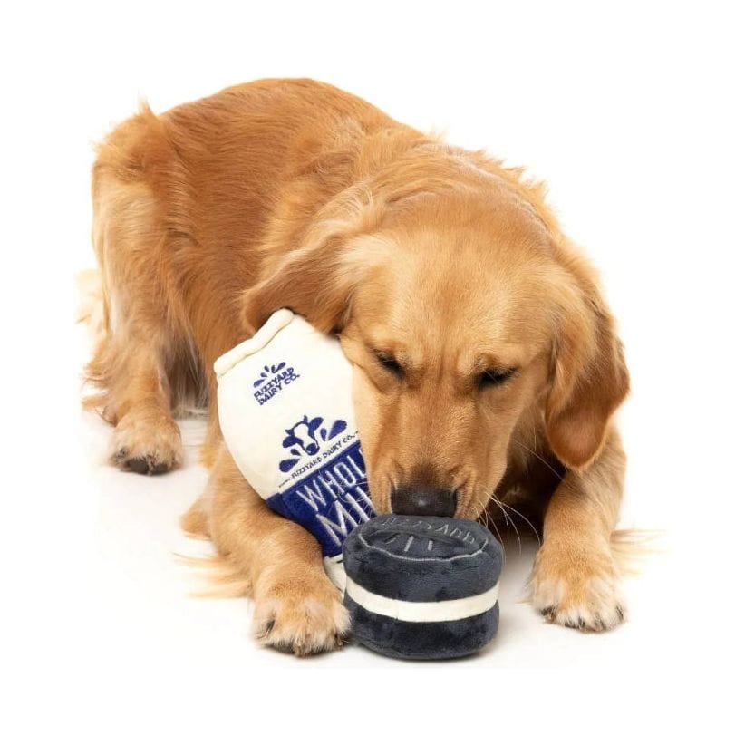 Plush whole milk bottle and dark cookie toy, hugged by golden dog