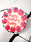 Pink birthday cake with “Happy Birthday Daisy” message and piped rosette frosting