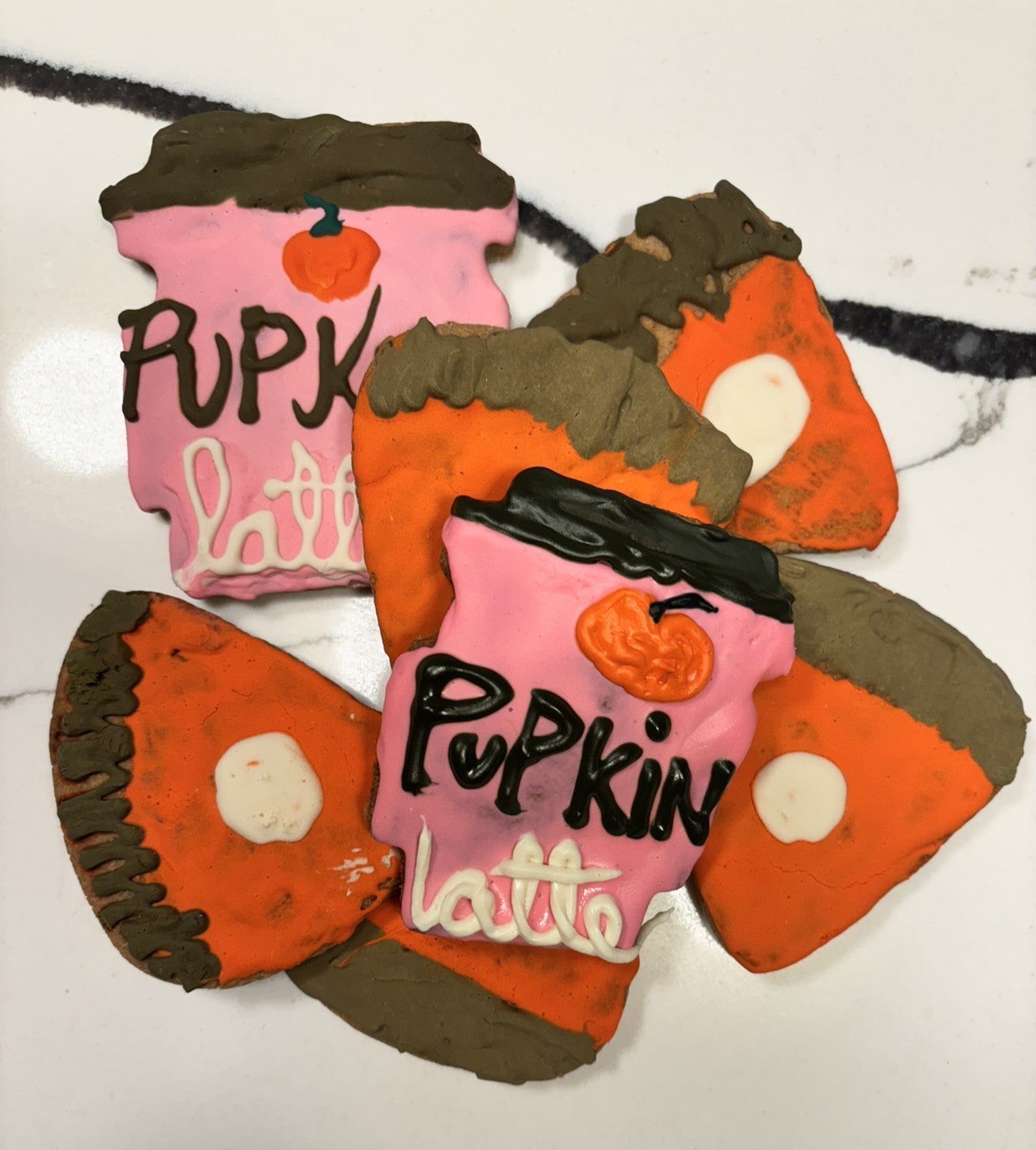 Pumpkin latte dog cookies in orange, dark brown, and pink with white icing centers