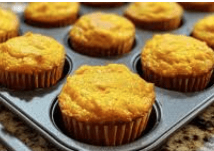 Pumpkin muffins in baking cups on a tray, golden tops
