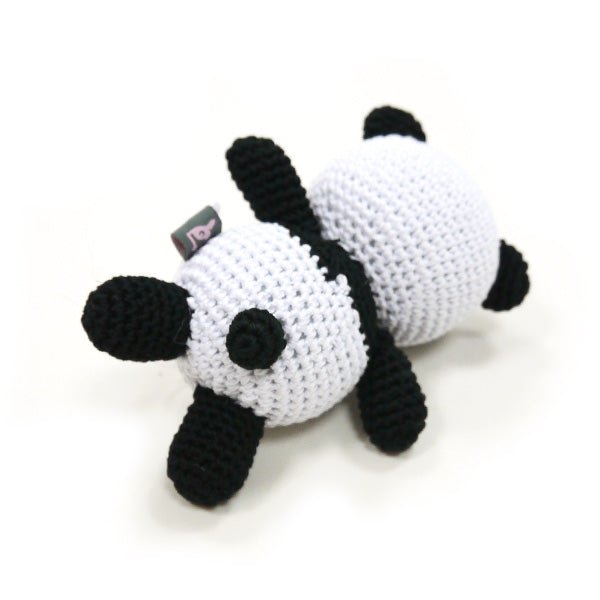 Crochet panda toy from the side with a small fabric tag, black and white stitched limbs.